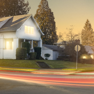 View of a suburban corner lot home with car trails