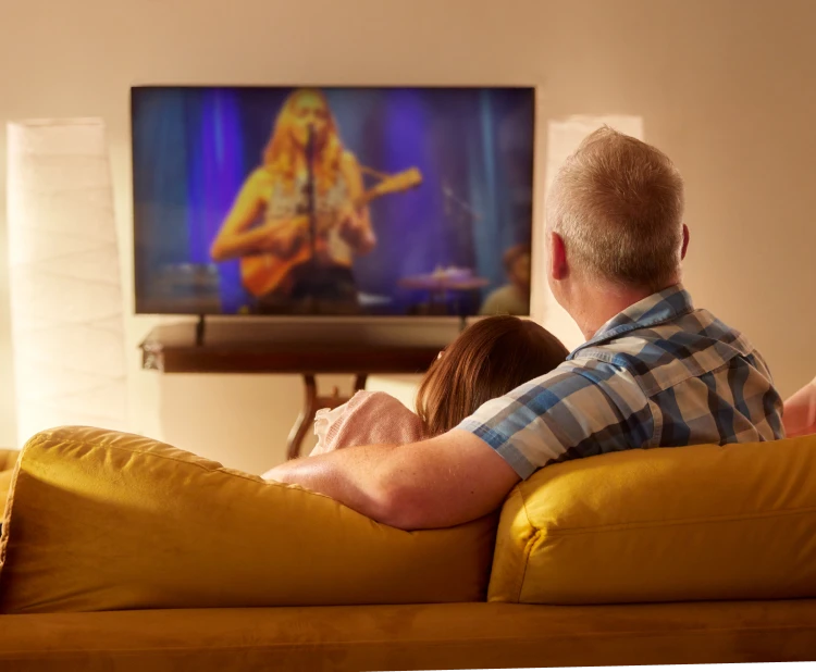 A girl and her dad sit on the couch and watching the favorite show on TV powered by Brightspeed internet.