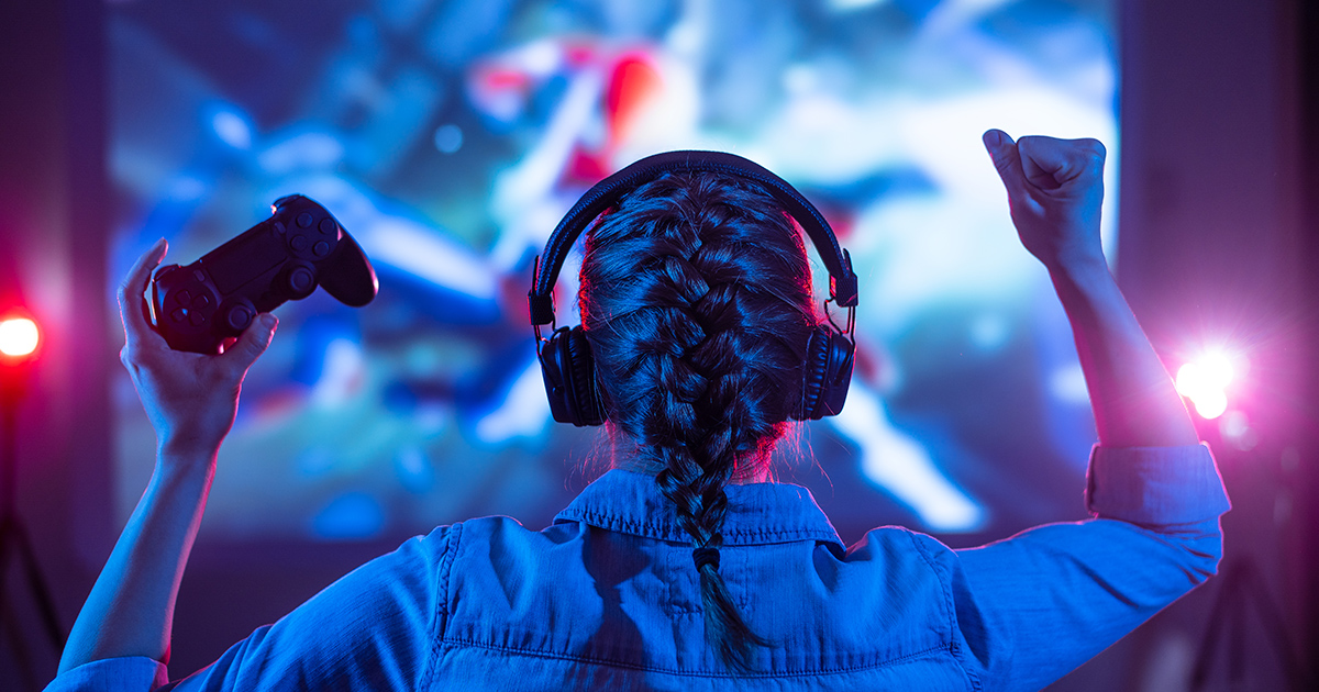 A woman cheers while playing a video game on a big-screen console